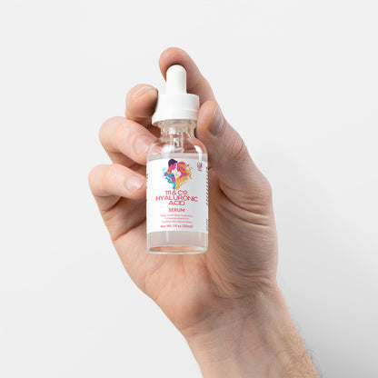 A hand holds a small, clear dropper bottle labeled 111 & COMPANY HYALURONIC ACID SERUM, promising skin rejuvenation. The label features colorful graphics, with a white cap and dropper. The transparent liquid offers hydration, set against a light gray backdrop that highlights its purity.