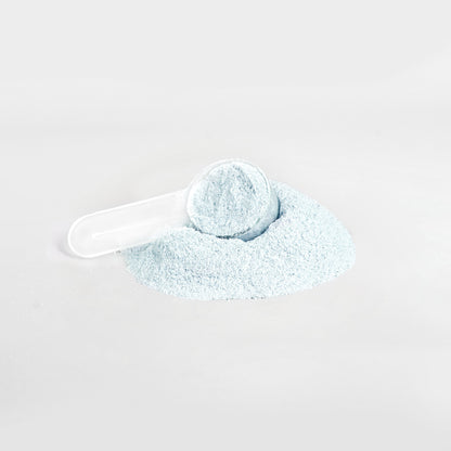 A white plastic scoop is partially buried in a small pile of 111 & Company Hydration Powder (Matcha Green Tea) against a plain white background. The finely textured, electrolyte-rich powder is scattered loosely, suggesting precise measuring or dispensing.