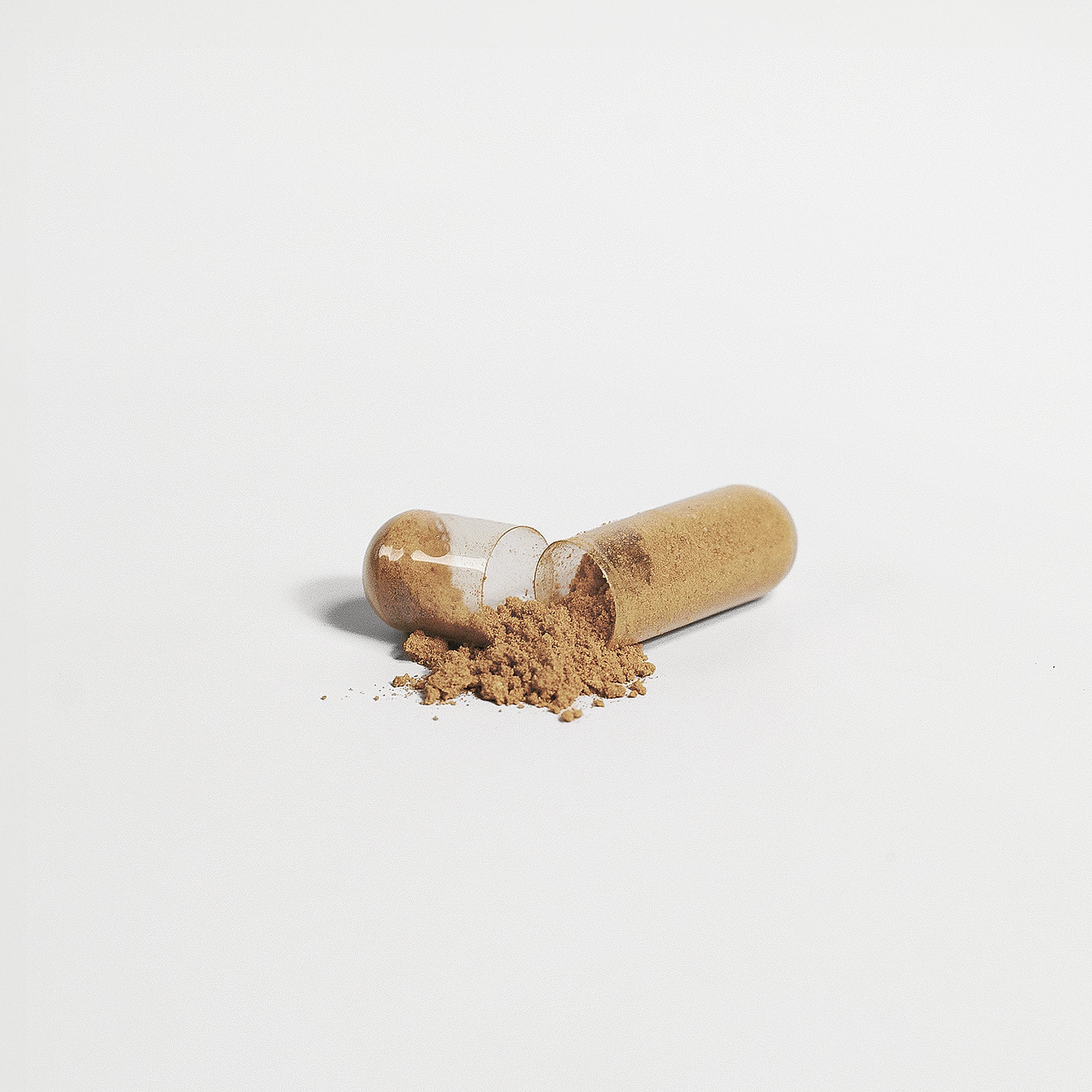 A transparent capsule of 111 & COMPANY LIVER SUPPORT CAPSULES by 111 & Company lies on a white backdrop, spilling light brown detox powder. The emptier half is on the left, creating a small mound next to the intact right half.