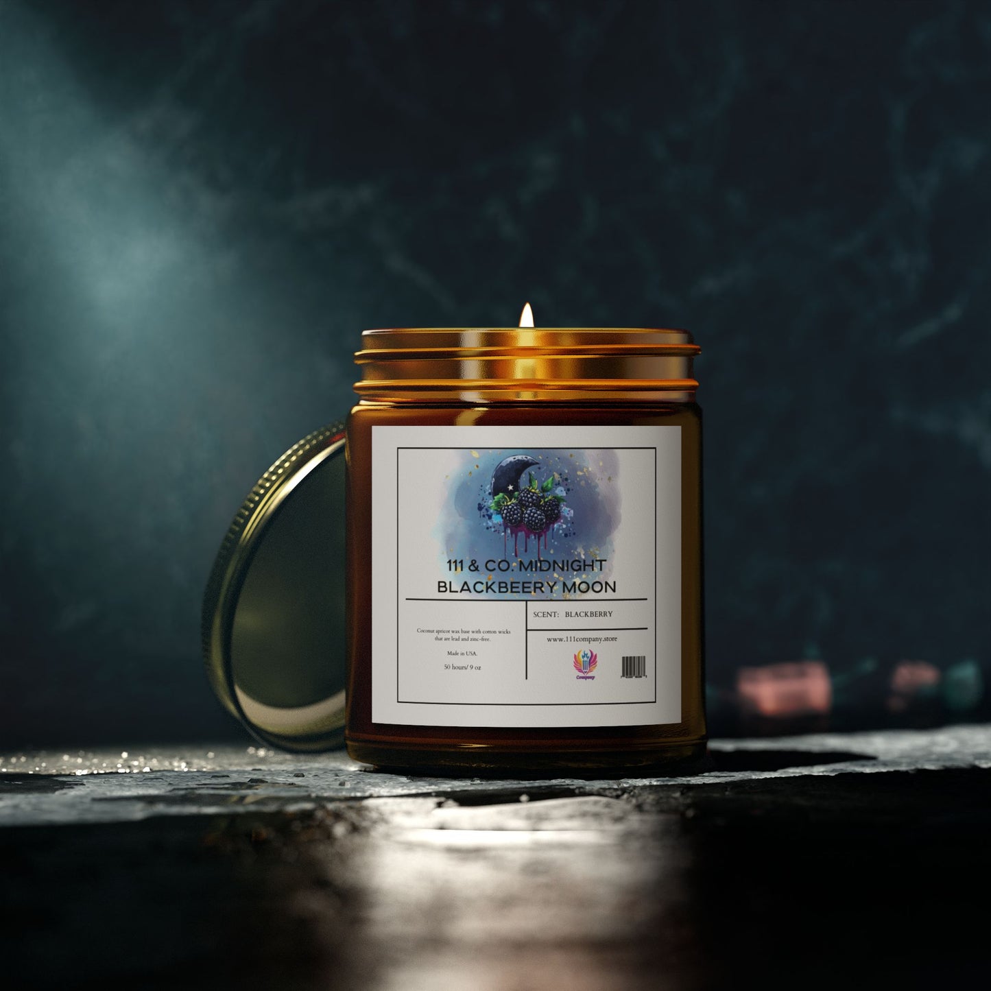 The 9oz  111 & Company Midnight Blackberry Moon Scented Candle in an amber jar casts a warm glow and fruity scent. The moon and tree watercolor label complements its gold lid on a textured dark surface, with blurred lights adding ambiance.