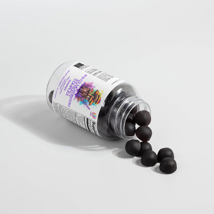 A transparent bottle labeled with 111 & COMPANY MUSHROOM COMPLEX GUMMIES rests on its side, scattering round, black gummies over a white surface. The label displays vibrant graphics and text, while shadows from the bottle and gummies enhance the simple, clean setup.
