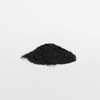 A small mound of 111 & COMPANY GUT WELLNESS POWDER by 111 & Company, enriched with fulvic acid, sits on a smooth white surface. The fine black powders granular texture highlights its potential digestive benefits against the plain background.