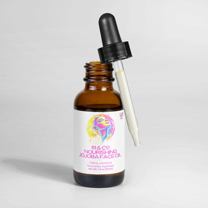 The 111 & COMPANY NOURISHING JOJOBA FACE OIL by 111 & Company stands upright, featuring an illustrated face on the label. The dropper cap rests against the glass bottle filled with luxurious jojoba seed oil, presented elegantly against a plain white background.