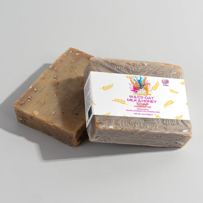 Two soap bars are shown; one is unwrapped, displaying a textured brown surface with small spots. The other is partially wrapped in clear plastic, labeled 111 & COMPANY OAT MILK HONEY SOAP, ideal for sensitive skin with its nourishing formula and colorful graphics.