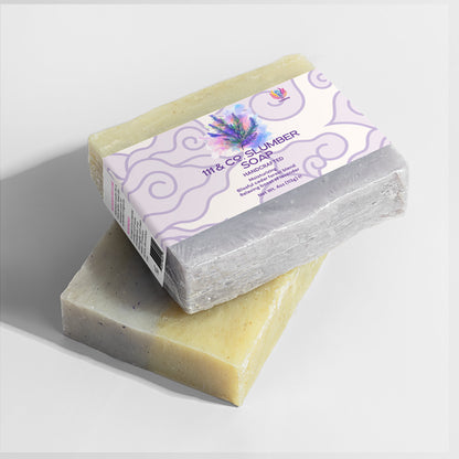 Two handcrafted soap bars are on a white surface. The top bar, wrapped in purple floral packaging, is labeled 111 & COMPANY SLUMBER SOAP from 111 & Company and has a lavender scent. The bottom bar is unwrapped, speckled, and rectangular.