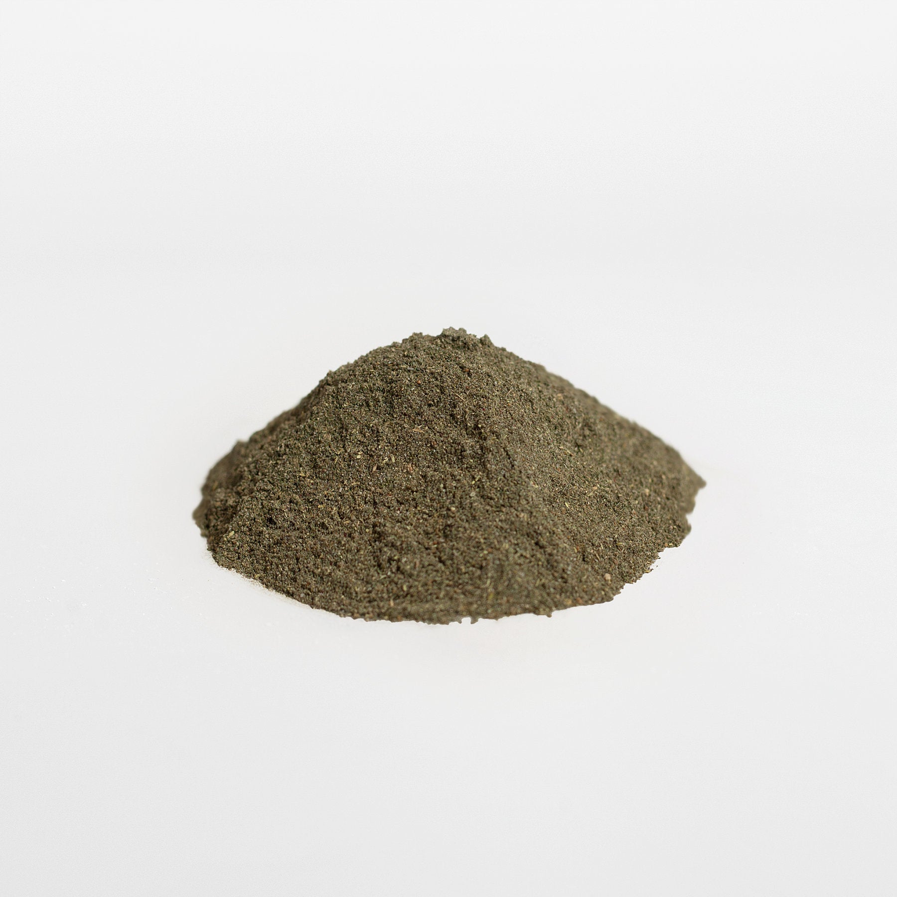 A small, conical mound of fine, dark green powder sits on a plain white surface. The smooth, matte texture is reminiscent of superfoods like the Ultra Cleanse Smoothie Greens from 111 & Company line. The uniform white background highlights the powders vibrant hue.