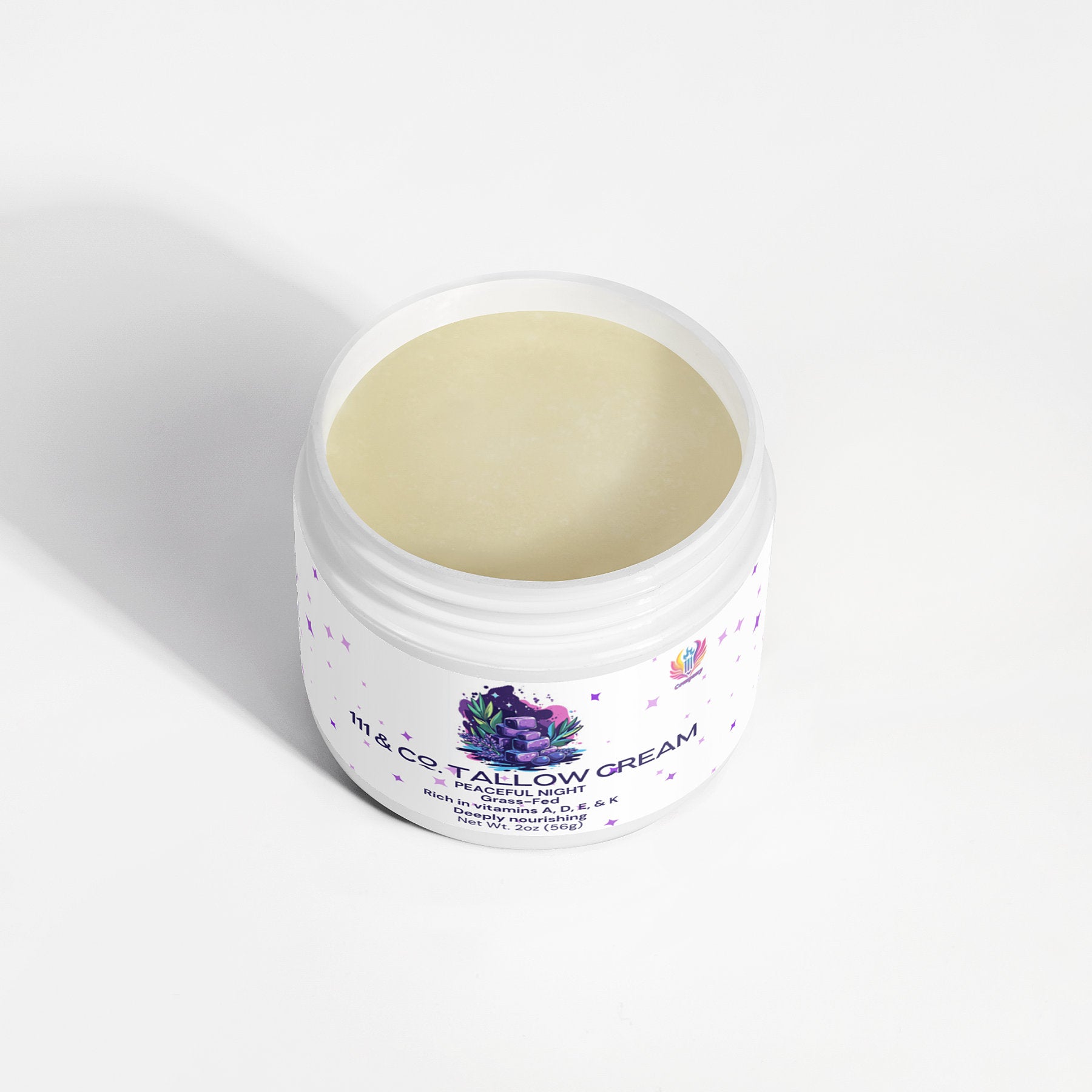 An open jar of 111 & Company Tallow Cream Peaceful Night by 111 & Company sits on a white surface, with colorful abstract artwork adorning the label. This pale yellow, smooth cream is designed for face, body, hands, and feet and is high in vitamin C and rich in fatty acids.