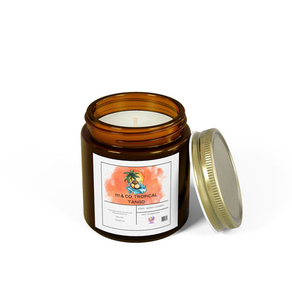 A clear jar holds a 111 & Co Coconut Mango Candle by 111 & Company. The label features a palm tree and orange watercolor. Made with eco-friendly coconut apricot wax and essential oils, its tropical aroma is delightful. The metallic lid rests beside the hand-poured 9oz candle.
