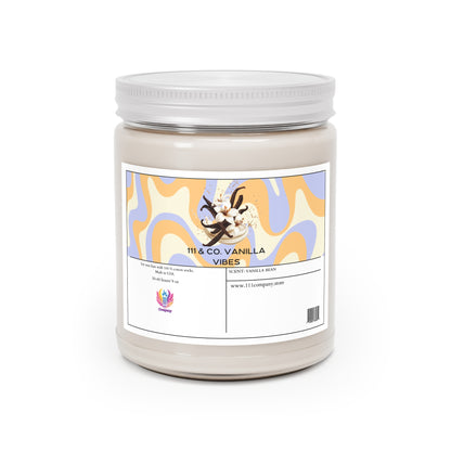 The 111 & COMPANY Vanilla Vibes candle, made from a soy wax blend, features abstract orange and blue waves and a vanilla bean image on its label. It has a shiny silver lid, and the bottom displays a colorful logo. The scent is vanilla bean.