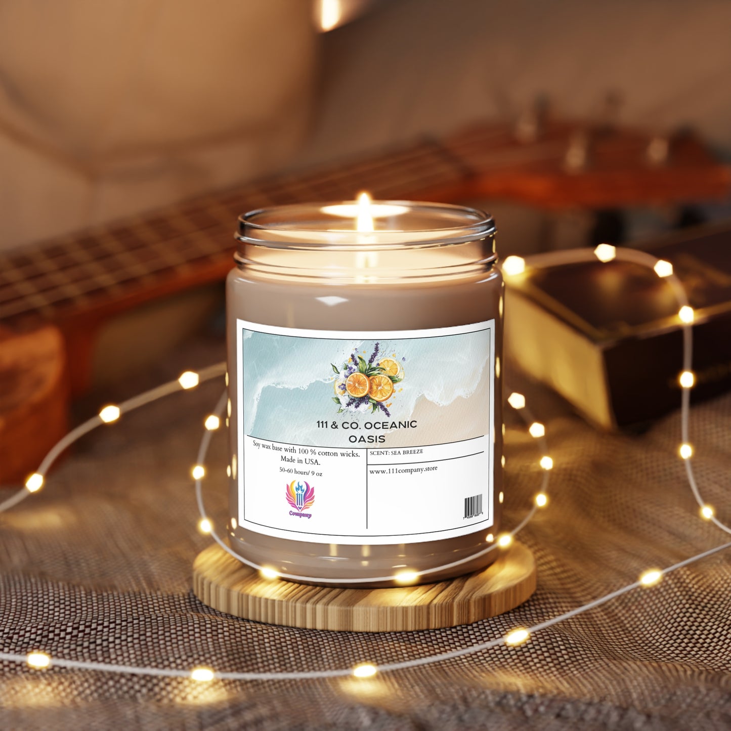 The 111 & Company Oceanic Oasis Sea Breeze scented candle by Printify rests on a wooden base amidst warm fairy lights, exuding a hint of lavender. Its label shows citrus fruits and waves, with a website link at the bottom. A blurred ukulele sits in the backdrop, creating a cozy ambiance.