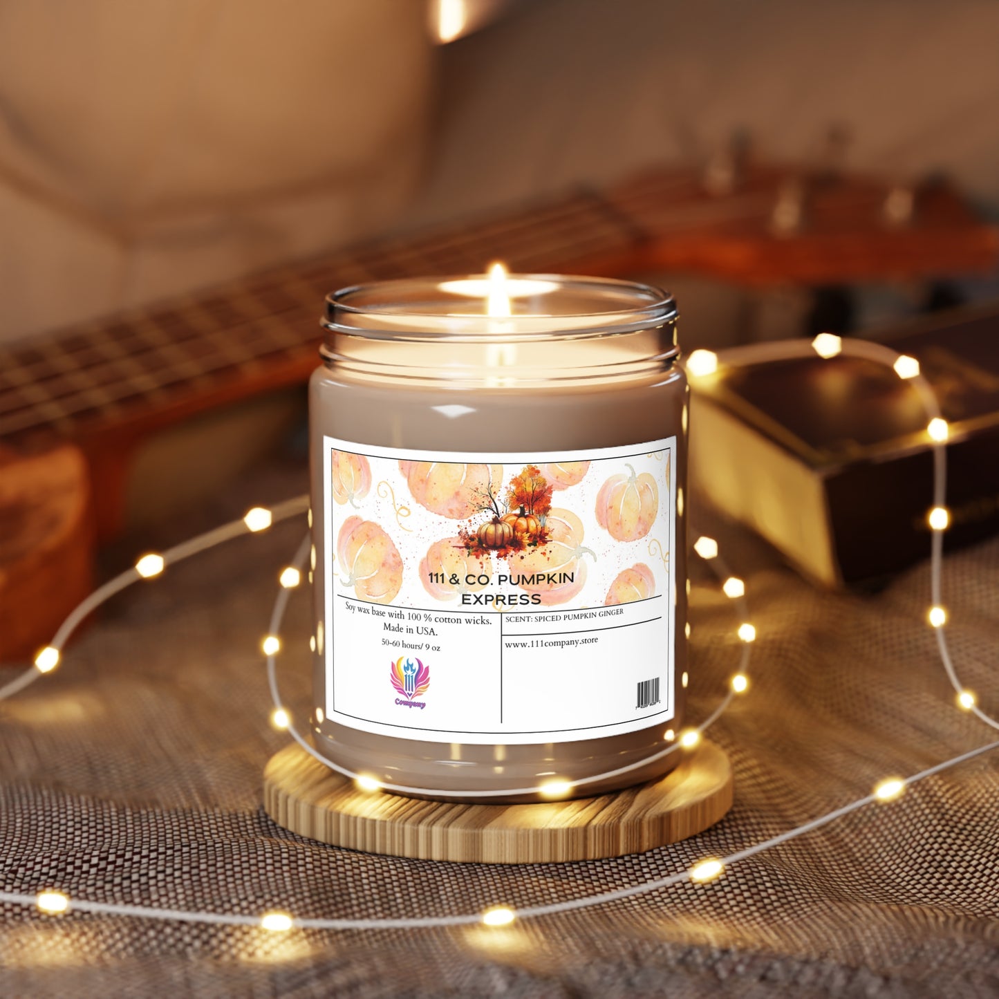 A Printify 111 & COMPANY Pumpkin Express Pumpkin Spice Soy Wax Scented Candle, 9oz, rests on a wooden coaster. The jar features pumpkins and autumn leaves, embodying falls essence. Warm fairy lights surround it, with a blurred guitar in the background for a cozy autumn vibe.