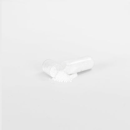 A clear capsule of 111 & COMPANY KETO BHB lies split open on a white background, its fine powder spilled out. This minimalist scene captures the clinical essence of Retro Fitness Supplements keto aid designed for supporting ketosis transition.