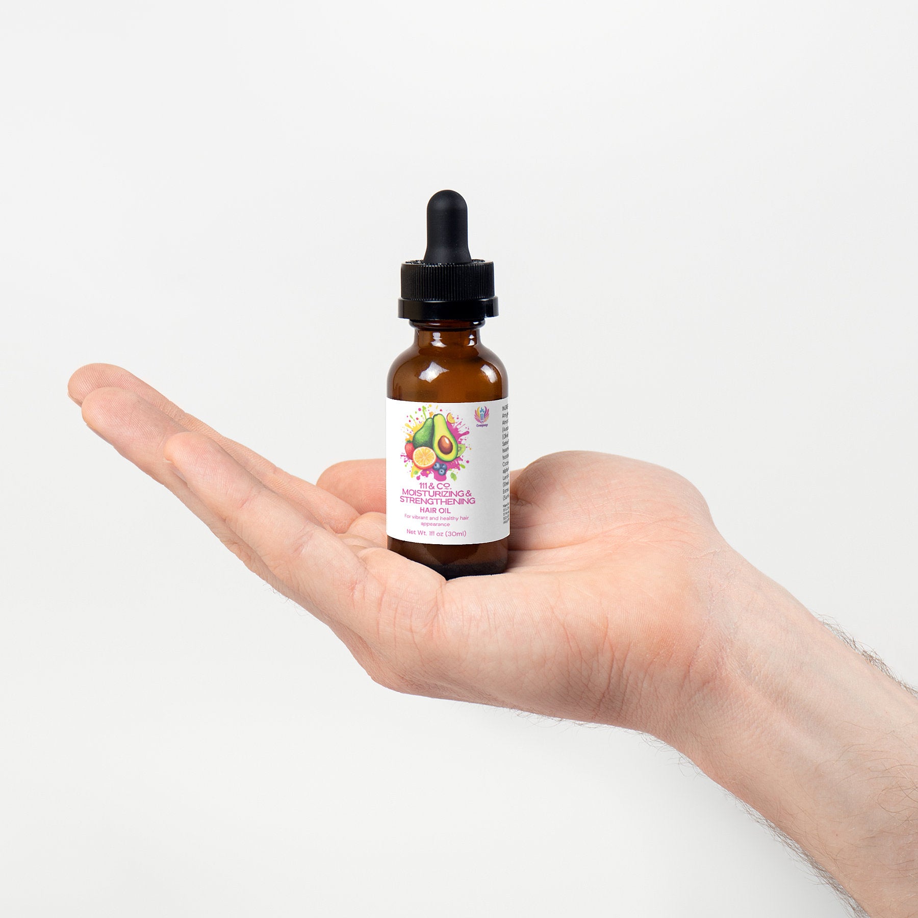 A hand holds a small amber dropper bottle with a black cap against a white background. The label features avocados and pink text, identifying it as Retro Fitness Supplements 111 & Company Moisturizing and Strengthening Hair Oil, ideal for nourishing natural hair.