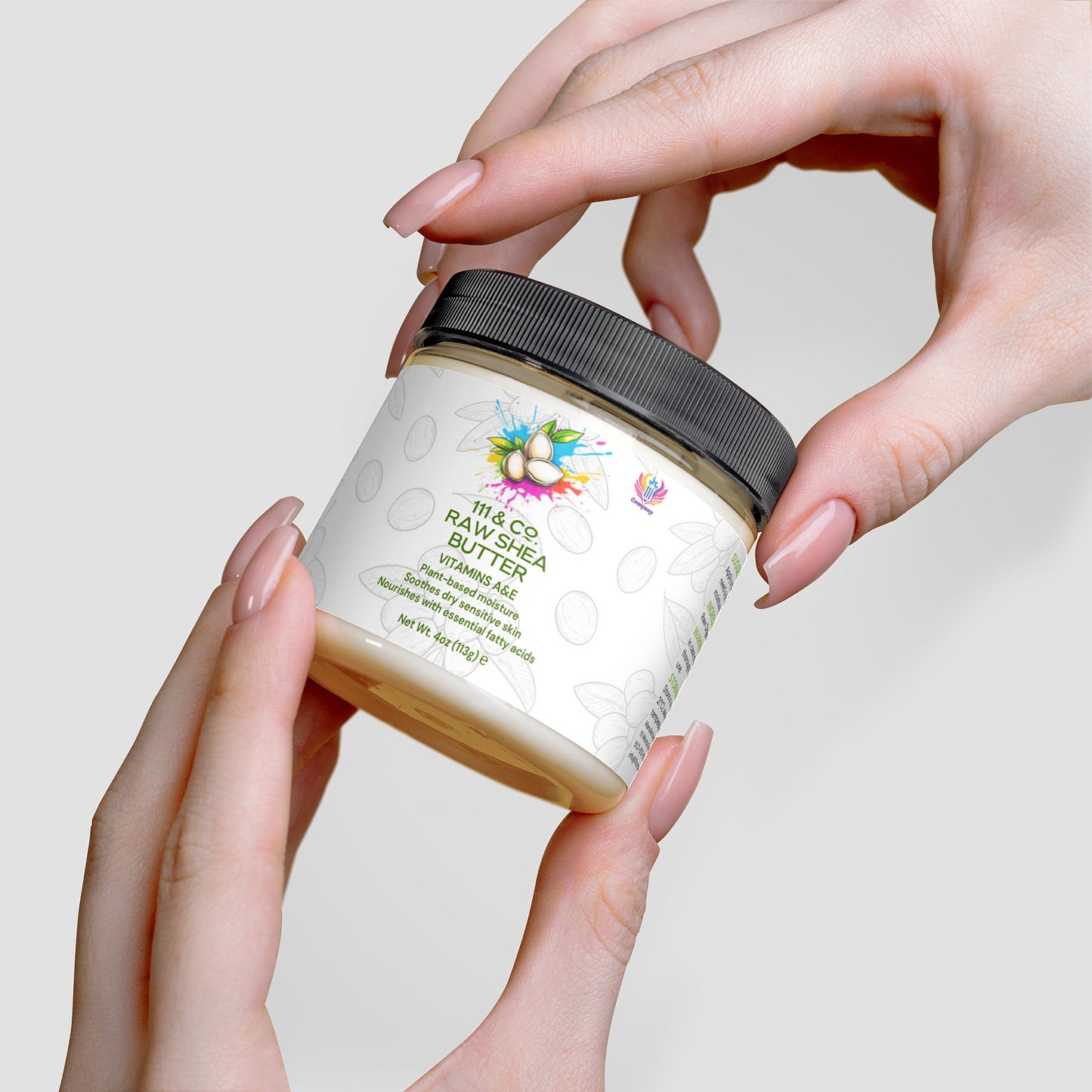 Hands gently cradle a jar labeled 111 & COMPANY RAW SHEA BUTTER by Retro Fitness Supplements. Unrefined shea butter, featuring Vitamin E and adorned with shea nut illustrations, is presented against a light gray background alongside soft hands and a gray lid.