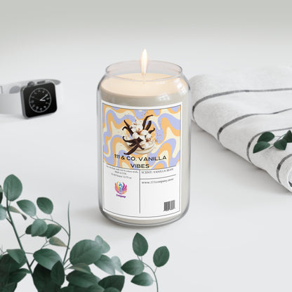 A 111 & COMPANY Vanilla Vibes candle, resembling a soda can and enriched with vanilla and tonka bean scents, sits with a striped towel, smartwatch, and eucalyptus branches on a soft white surface.